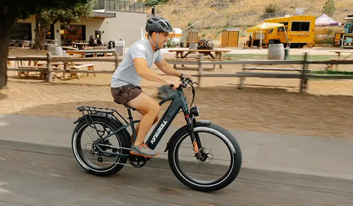 A man riding a Kingbull electric bike on a paved road.