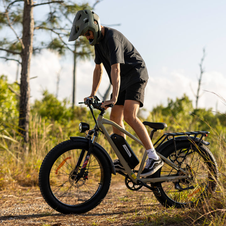 Person wearing helmet riding Kingbull Hunter 2.0 electric bicycle on dirt path in natural outdoor