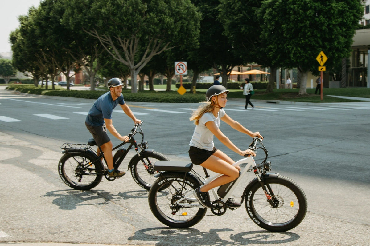 Man and woman riding separate Kingbull Hunter mountain electric bikes together on the road