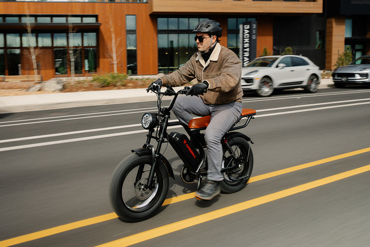 Man riding a Kingbull Ranger electric bike on a city street with buildings and cars in the background