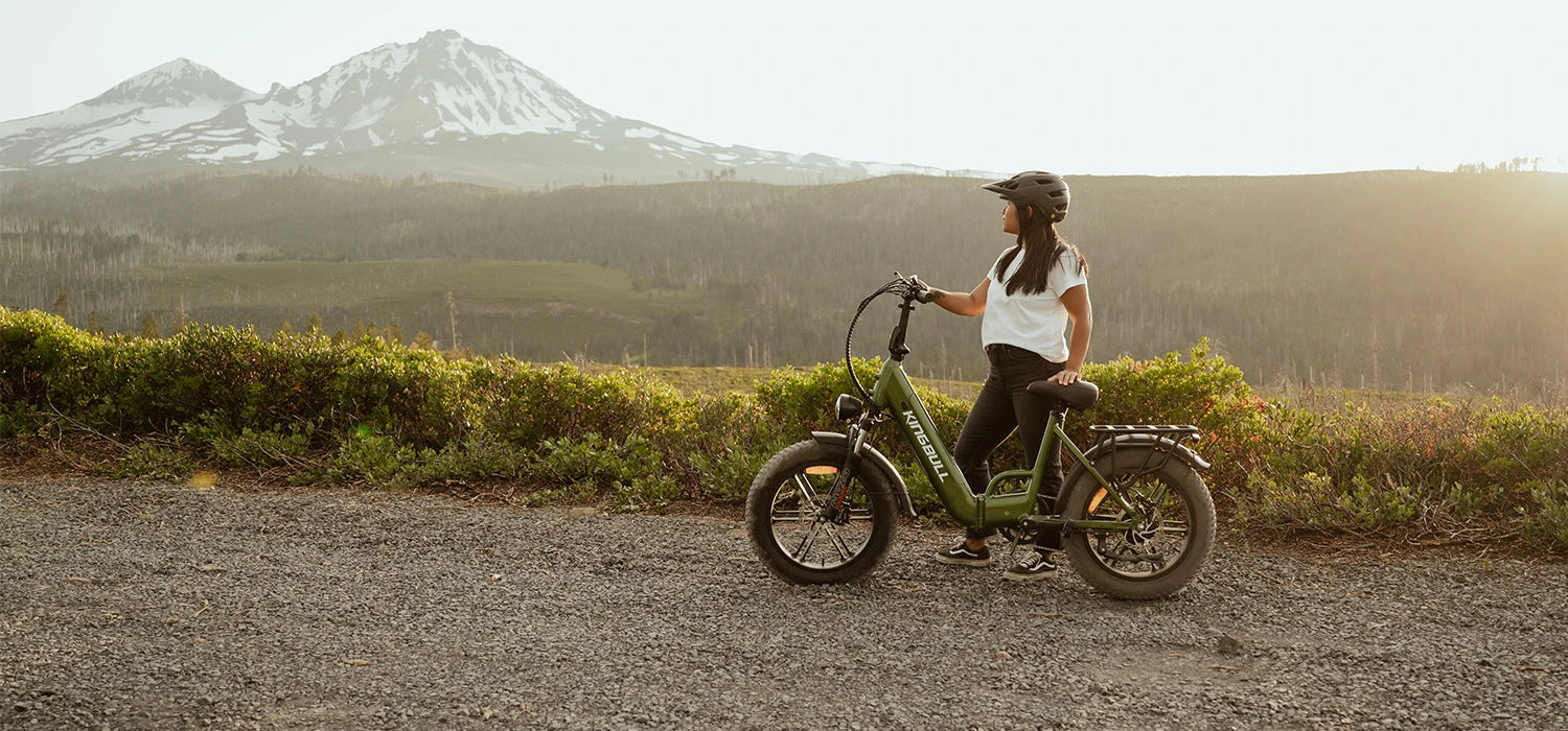 Female rider enjoying the scenery in the mountains, next to her is her kingbulkll green folding electric bike