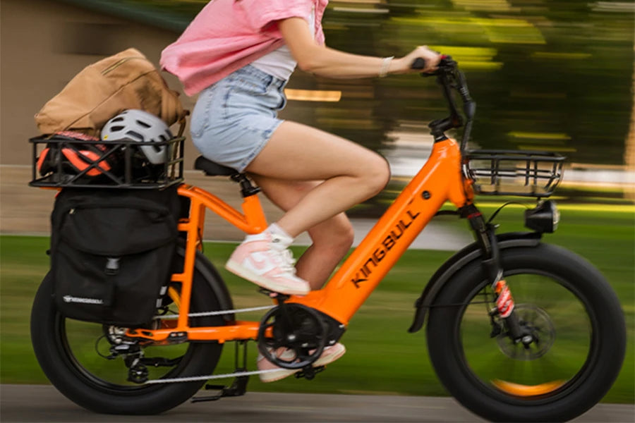 Girl pedals orange freight electric bicycle voyager 2.0 feels the power provided by torque.