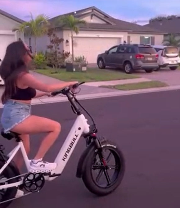 Lady is riding a white kingbull electric bike