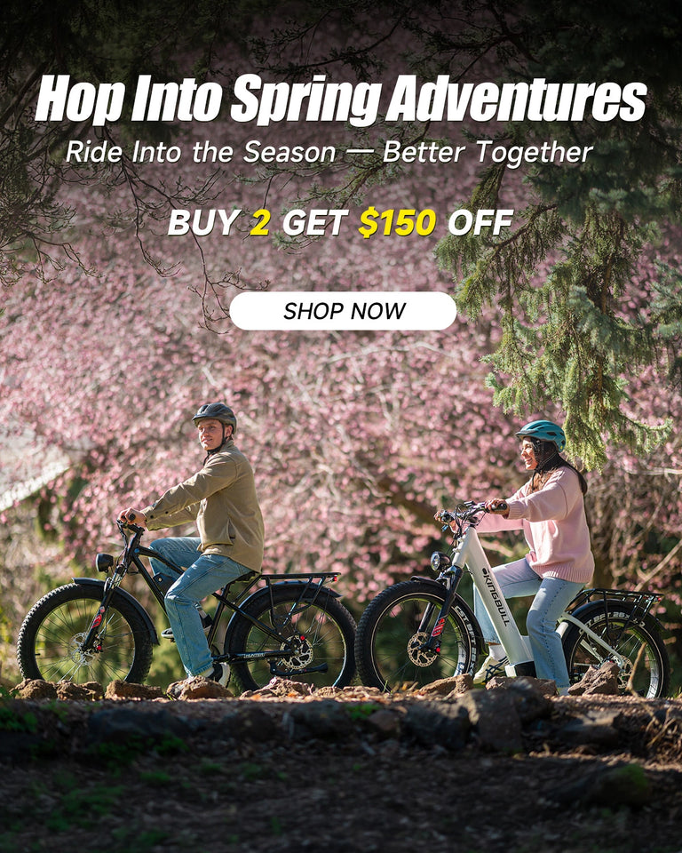 Easter Sale - Couple riding Kingbull hunter 2.0 off-road fat tire e-bike and Kingbull Discover ST 2.0 E-bike together on a scenic trail surrounded by spring cherry blossoms — Buy 2 Get $150 Off