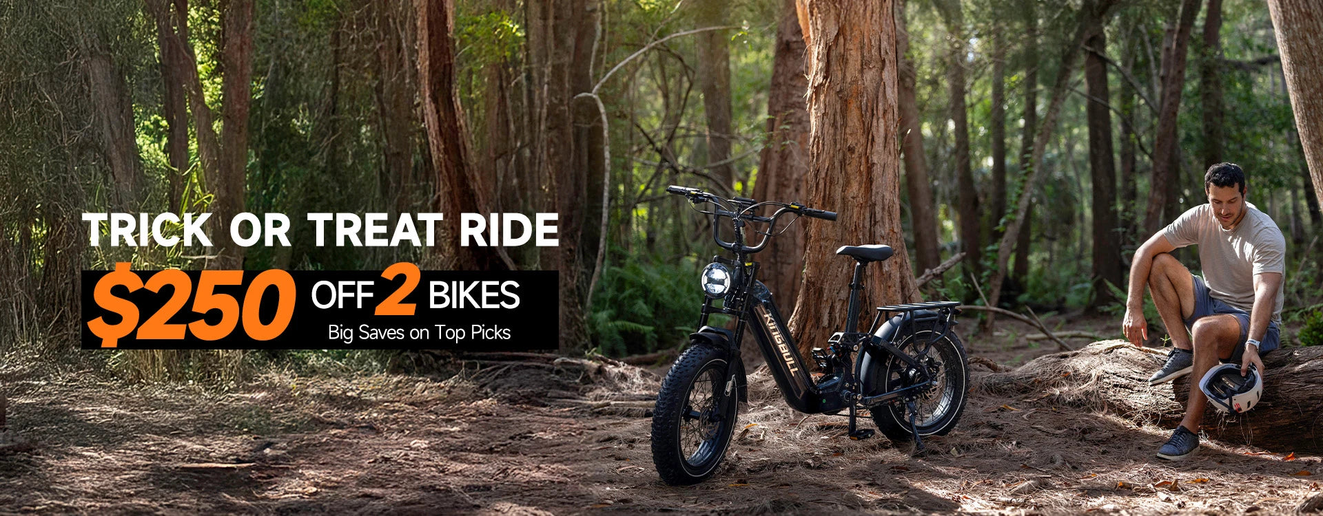 Gray Kingbull Jumper Go electric bike on forest trail with man resting - Trick or Treat promotion $250 off 2 bikes