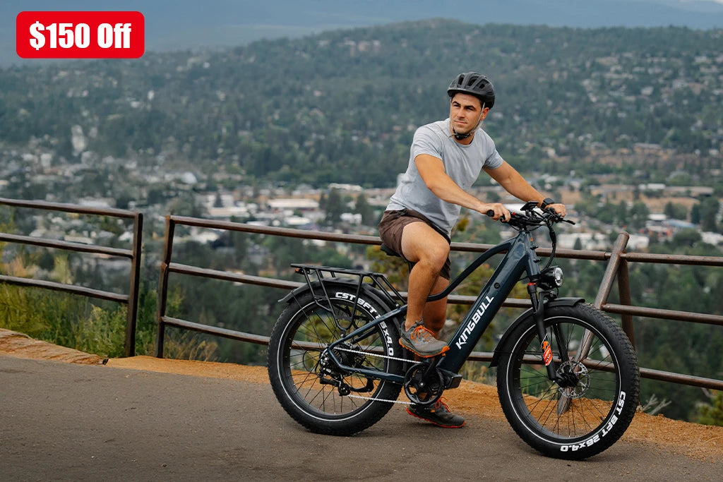 Man riding black Kingbull Discover 2.0 electric bike on scenic mountain overlook with city valley view - $150 off promotion