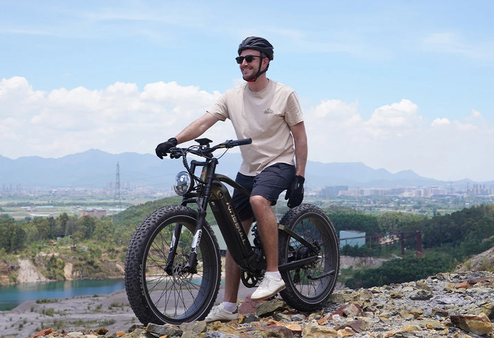 Man with Kingbull EX Titan Premium Full Suspension Electric Mountain Bike overlooking city skyline from mountain viewpoint