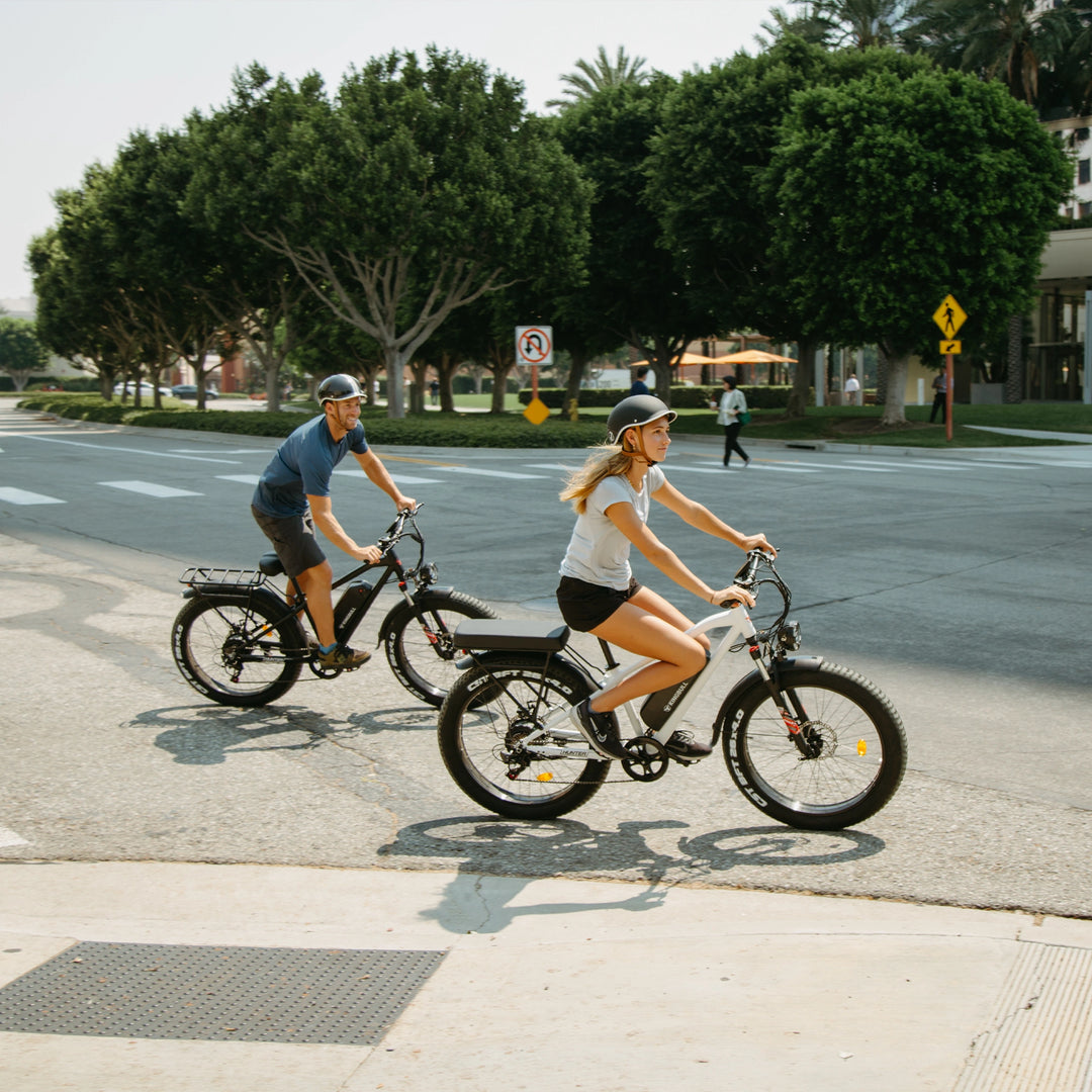 Man and woman riding separate Kingbull Hunter mountain electric bikes together on the road