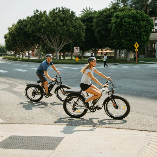 Man and woman riding separate Kingbull Hunter mountain electric bikes together on the road